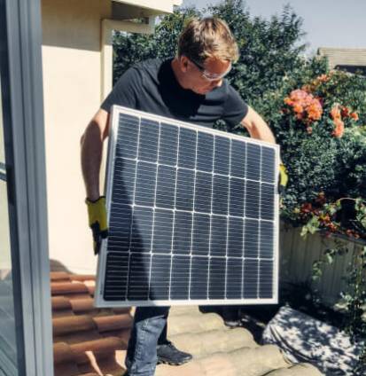 Instalador cargando unha placa solar